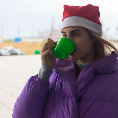 Pretty young girl drinks coffee or tea, streetの写真素材