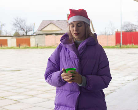 Pretty young girl drinks coffee or tea, street