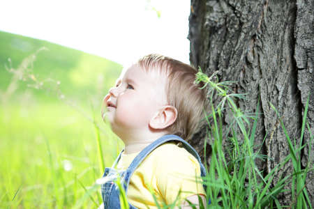 happy little boy sitting on the grass in the parkの写真素材
