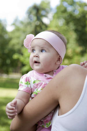 cute baby-girl outdoors on arms of her motherの写真素材