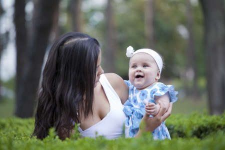 young mother relaxing outdoors looking happy and smiling holding her babyの写真素材