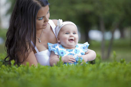 young mother relaxing outdoors looking happy and smiling holding her babyの写真素材