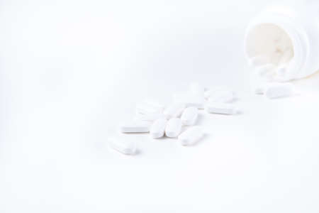 High key shot of white pills brightly lit on white backgroundの写真素材