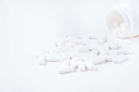 High key shot of white pills brightly lit on white backgroundの写真素材