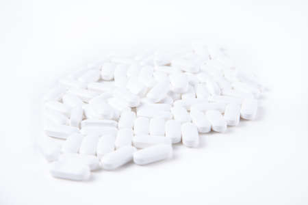 High key shot of white pills brightly lit on white backgroundの写真素材
