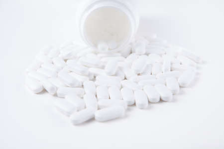 High key shot of white pills brightly lit on white backgroundの写真素材