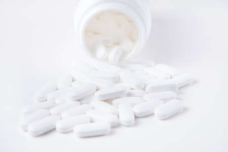 High key shot of white pills brightly lit on white backgroundの写真素材