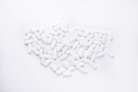 High key shot of white pills brightly lit on white backgroundの写真素材