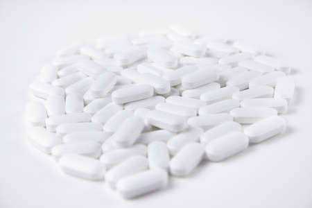 High key shot of white pills brightly lit on white backgroundの写真素材