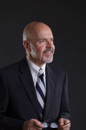businessman in dark blue suit holding glassesの写真素材