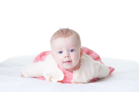 Cute baby-girl in pink dress, on her tummy isolatedの写真素材