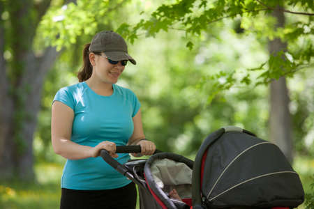 Young mother standing with stroller in the park