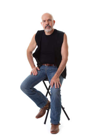 Mature biker sitting on the chair, serious look, isolated on whiteの写真素材