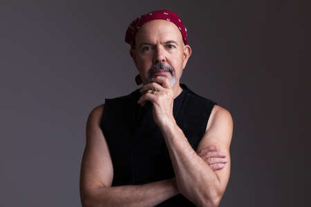 Mature biker in red bandana  fold his hands, serious look, thinkingの写真素材
