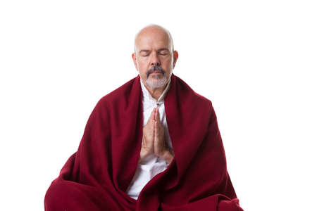 Mature male in the red shawl doing yoga/meditation with closed eyes, isolated on whiteの写真素材