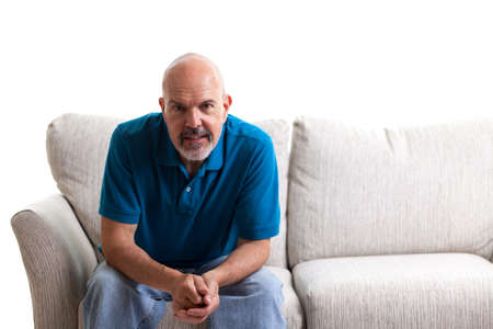 Portrait of mature man sitting on the couch isolated on whiteの写真素材