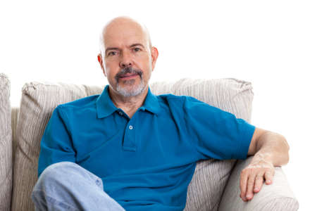 Portrait of mature man sitting on the couch isolated on whiteの写真素材