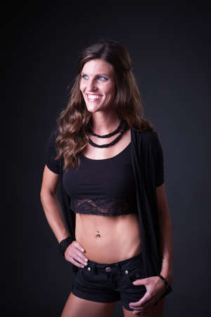 Beautiful woman in jeans and sleeveless shirt, studio portrait on dark background.の写真素材