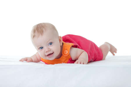 Cute baby-girl in dress, on her tummy isolatedの写真素材