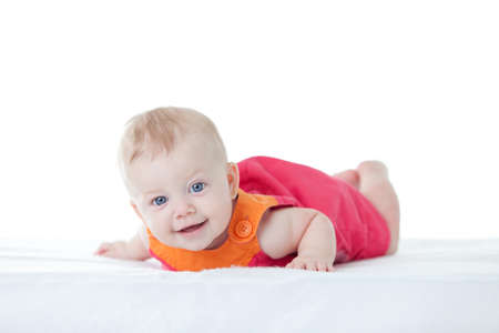 Cute baby-girl in dress, on her tummy isolatedの写真素材