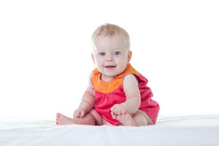 Little cute baby-girl in dress, sitting, isolatedの写真素材