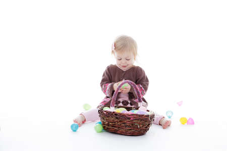 Little girl sitting on the floor playing with Easter eggs, isolated on white background