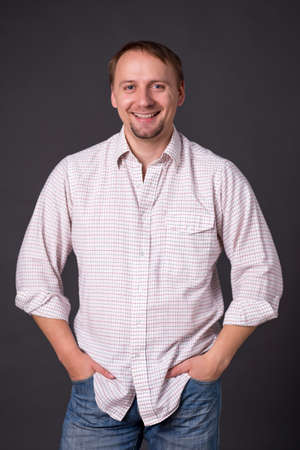 Man in long sleeved shirt, hands in pockets, isolated on greyの写真素材