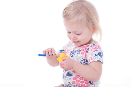 toddler girl brushing duck teeth, isolated on whiteの写真素材