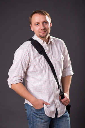 Man in long sleeved shirt, holding a bag, isolated on greyの写真素材