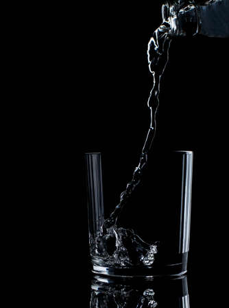 pouring water on a glass on black background drink, mineralの写真素材