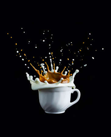 Splash of coffee and milk in white cupの写真素材
