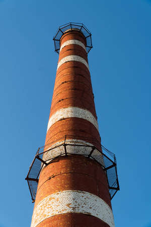 Isolated old aged weathered tall industrial factory chimney, red grungy brick smokestack grunge vintageの写真素材