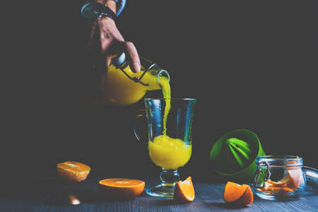 Man pouring fresh orange juice into a glassの写真素材