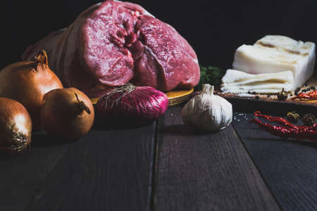 Raw meat, vegetables, and spices on dark wooden tableの写真素材
