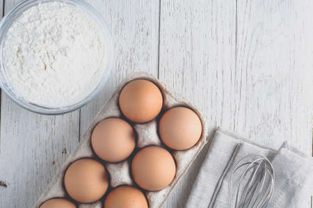 Eggs and ingredients for baking on a light wooden table. Top view and flat layの写真素材