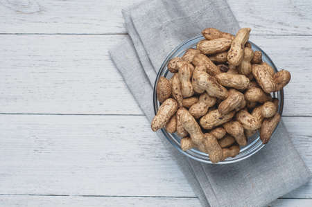 Peanuts in a jar on a white wooden backgroundの写真素材