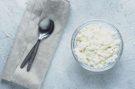 Fresh cottage cheese in a glass dish on a light background