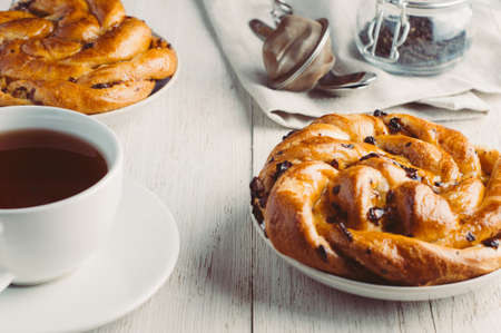 Cup of tea and bagel on white wooden background
