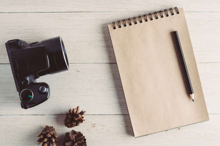 Photo camera and notebook on a white wooden backgroundの写真素材