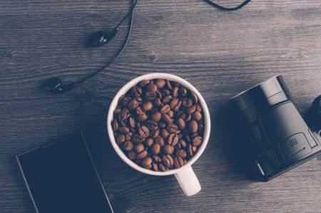 Cup with coffee grains and gadgets on dark wooden backgroundの写真素材