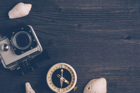 Old compass and action camera on a dark wooden background. The concept of direction or travelの写真素材