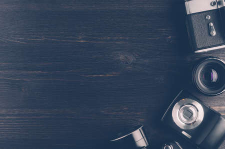 Photo cameras on a dark wooden background. The concept of the development of technology