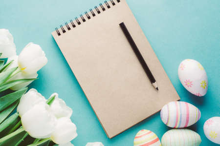 White tulips and Easter eggs on a green background. The concept of Easter or spring