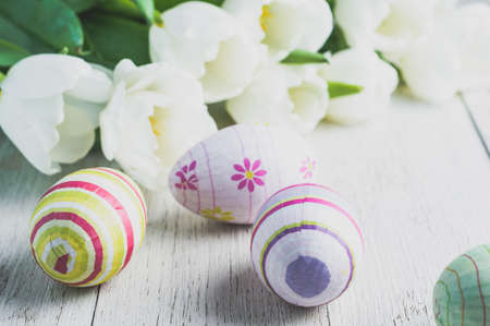 White tulips and Easter eggs on white wooden background. The concept of Easter or springの写真素材