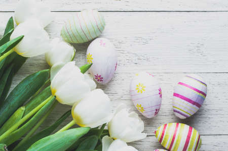 White tulips and Easter eggs on white wooden background. The concept of Easter or springの写真素材