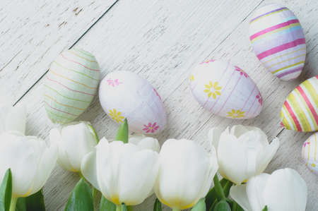 White tulips and Easter eggs on white wooden background. The concept of Easter or springの写真素材