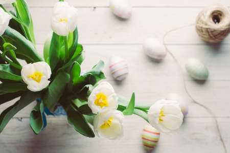 White tulips and Easter eggs on white wooden background. The concept of Easter or springの写真素材