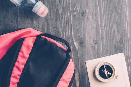 Old compass and a backpack on a dark wooden background