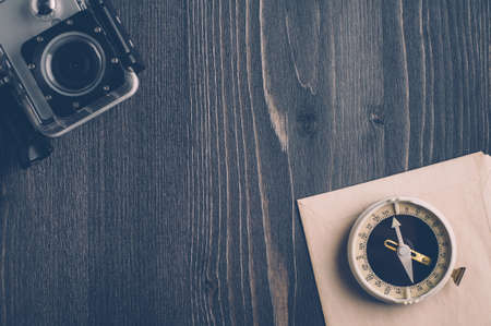 Old compass and camera on a dark wooden backgroundの写真素材