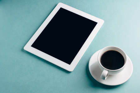 Cup of coffee and tablet PC on a green backgroundの写真素材